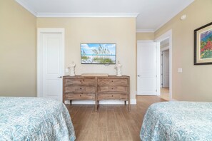 Un dormitorio con dos camas, un aparador, un cuadro y una puerta que da a otra habitación.