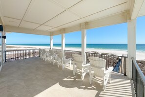 Un'area esterna riparata con sedie bianche e vista sulla spiaggia.