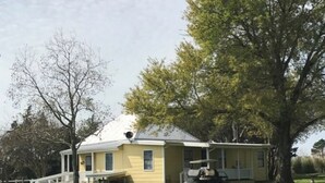 A single-story yellow house with a porch, a covered garage, and a lawn. - Perfect home in the country (Burton)