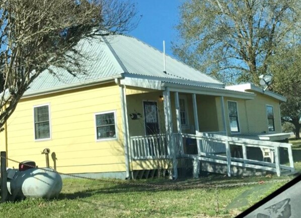 A yellow building with a metal roof, a porch, and a small attached structure. - Perfect home in the country (Burton)