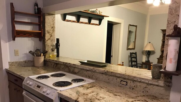 A kitchen with a granite countertop, a stove, a microwave, and a large mirror above the sink. - Perfect home in the country (Burton)