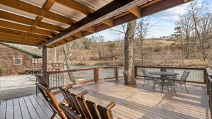 Une terrasse en bois avec une table et des chaises, donnant sur une rivière.