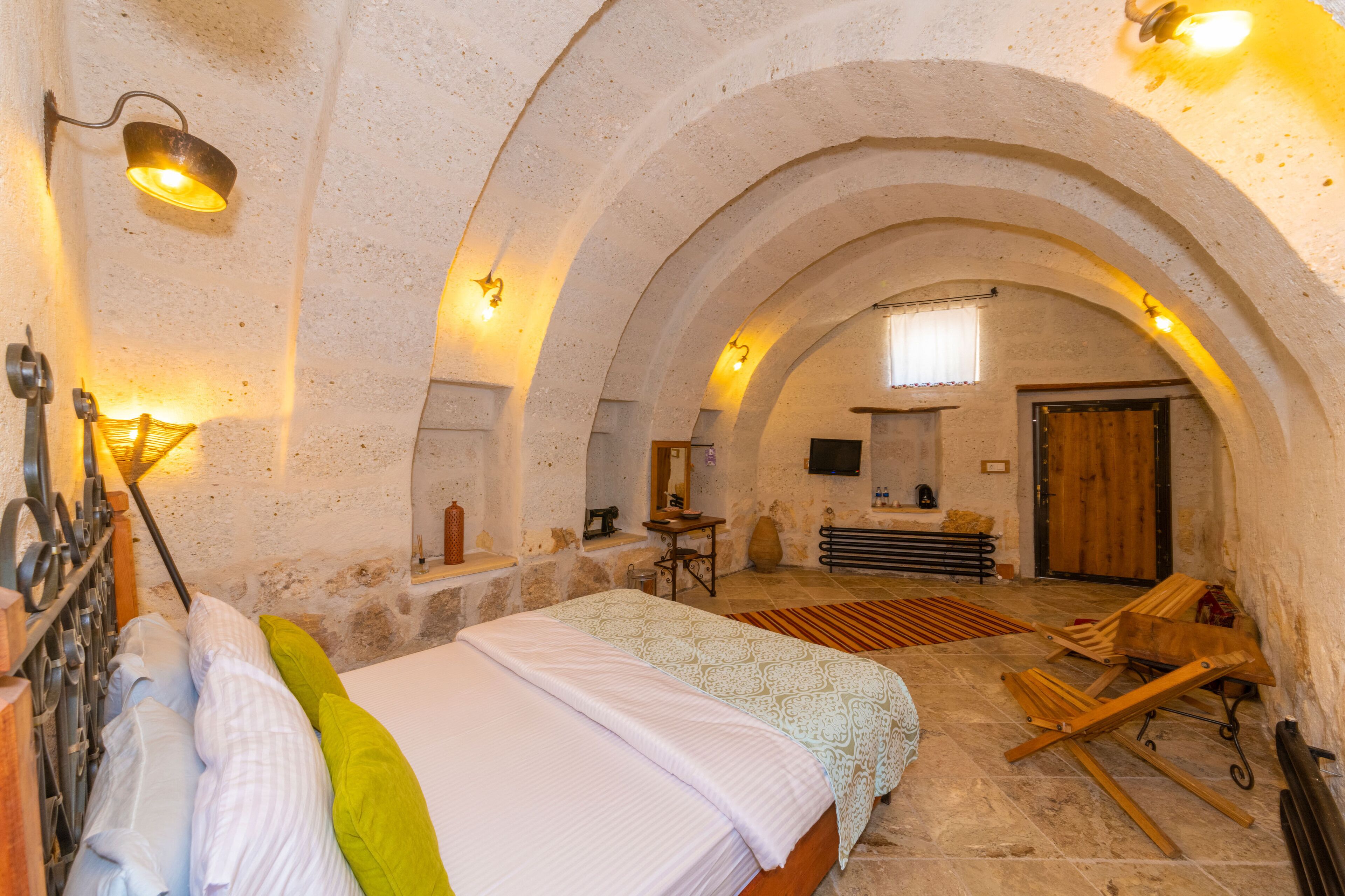 Un dormitorio acogedor y rústico con una cama grande, muebles de madera y un arco de piedra.
