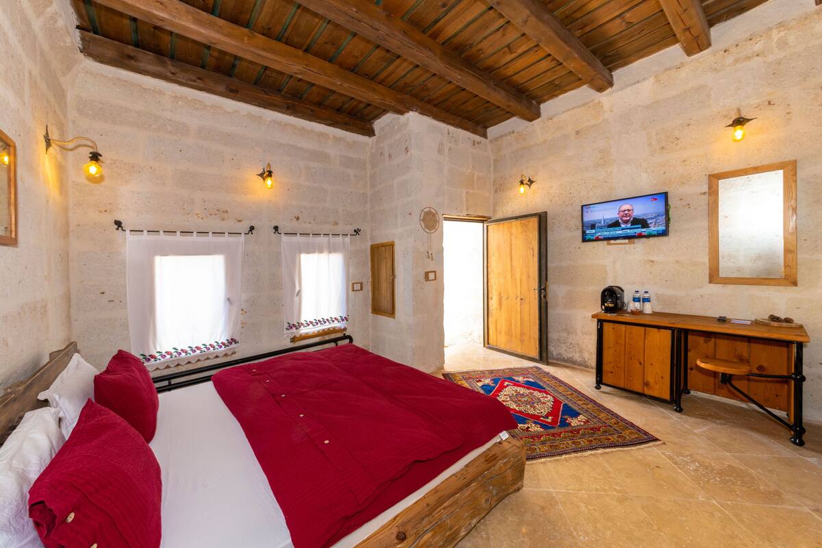 A bedroom with a wooden bed, a television, a wooden dresser, and a patterned rug.