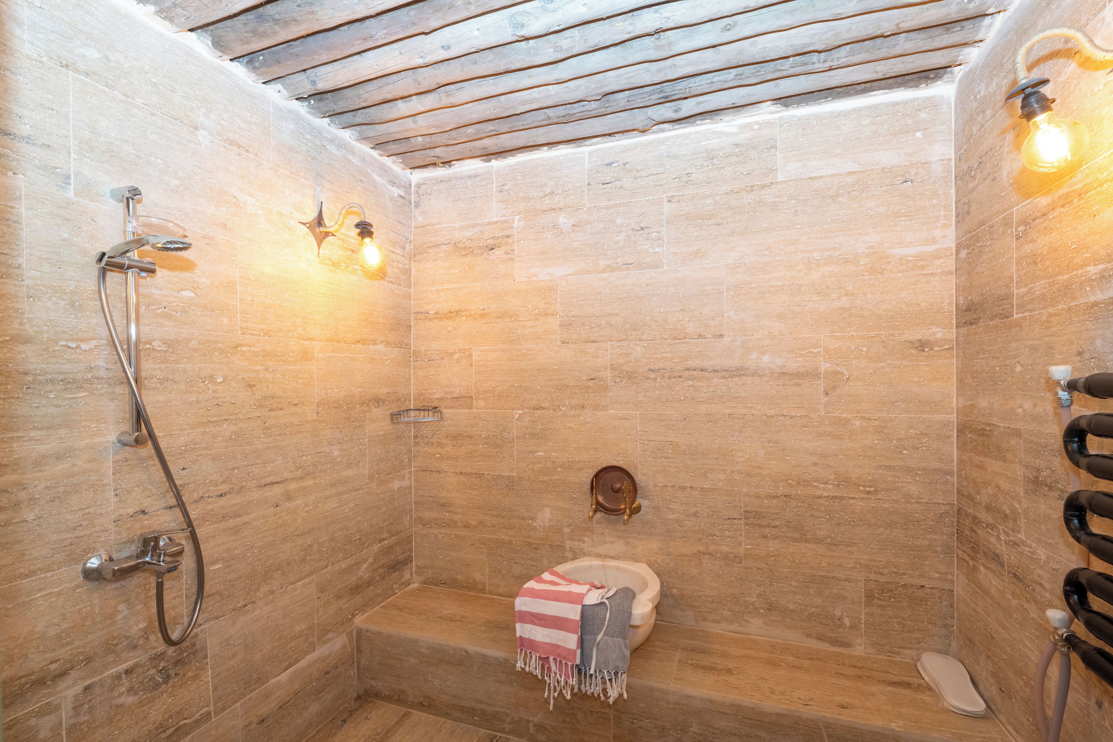 A shower with a wooden ceiling, a toilet, and a towel.