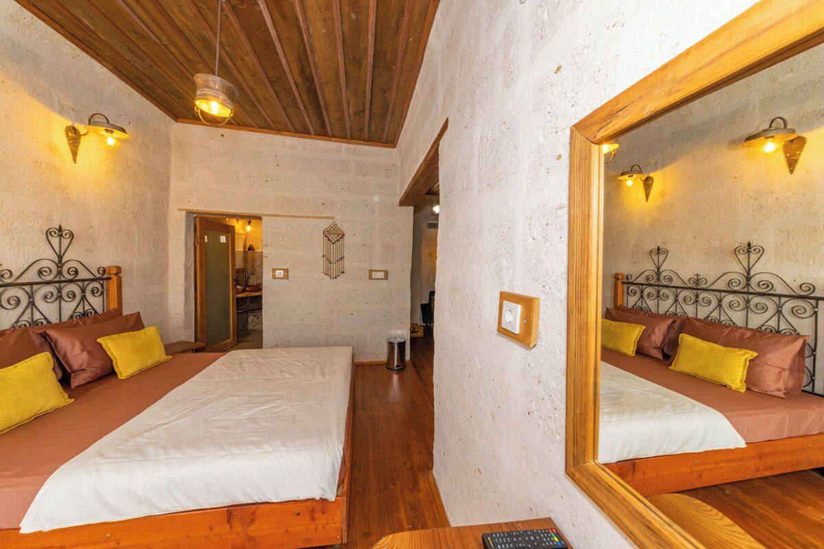 A bedroom with two beds, wooden flooring, and a large mirror on one wall.