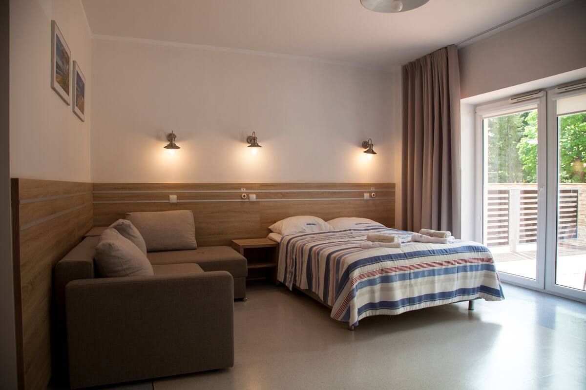 A modern bedroom with a bed, a sofa, and a nightstand.