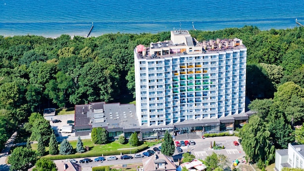 Un hôtel de grande hauteur doté de nombreux balcons, d’un parking et offrant une vue sur la mer.