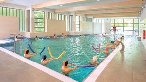 Une piscine intérieure dotée de plusieurs couloirs de nage, d’un poste de surveillance pour les sauveteurs et offrant une vue dégagée sur l’extérieur grâce à de grandes fenêtres.