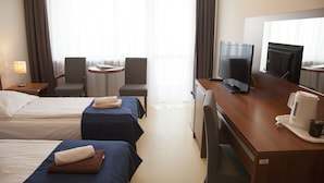 Une chambre d’hôtel avec deux lits, un bureau avec un ordinateur, une machine à café et une télévision.