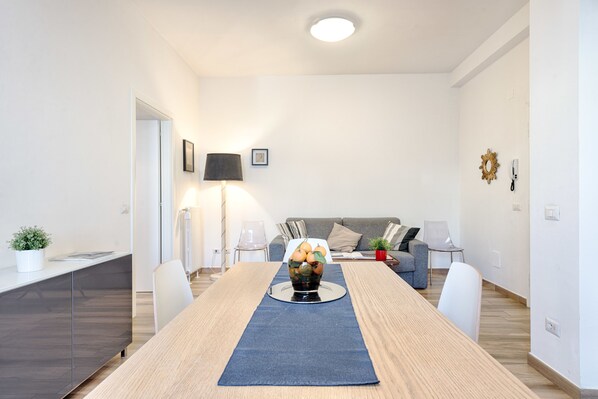 A modern living room with a dining table, sofa, and a lamp.