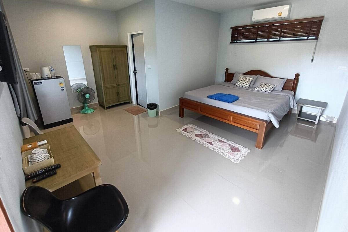 A bedroom with a bed, bedside table, and a small desk with a chair.