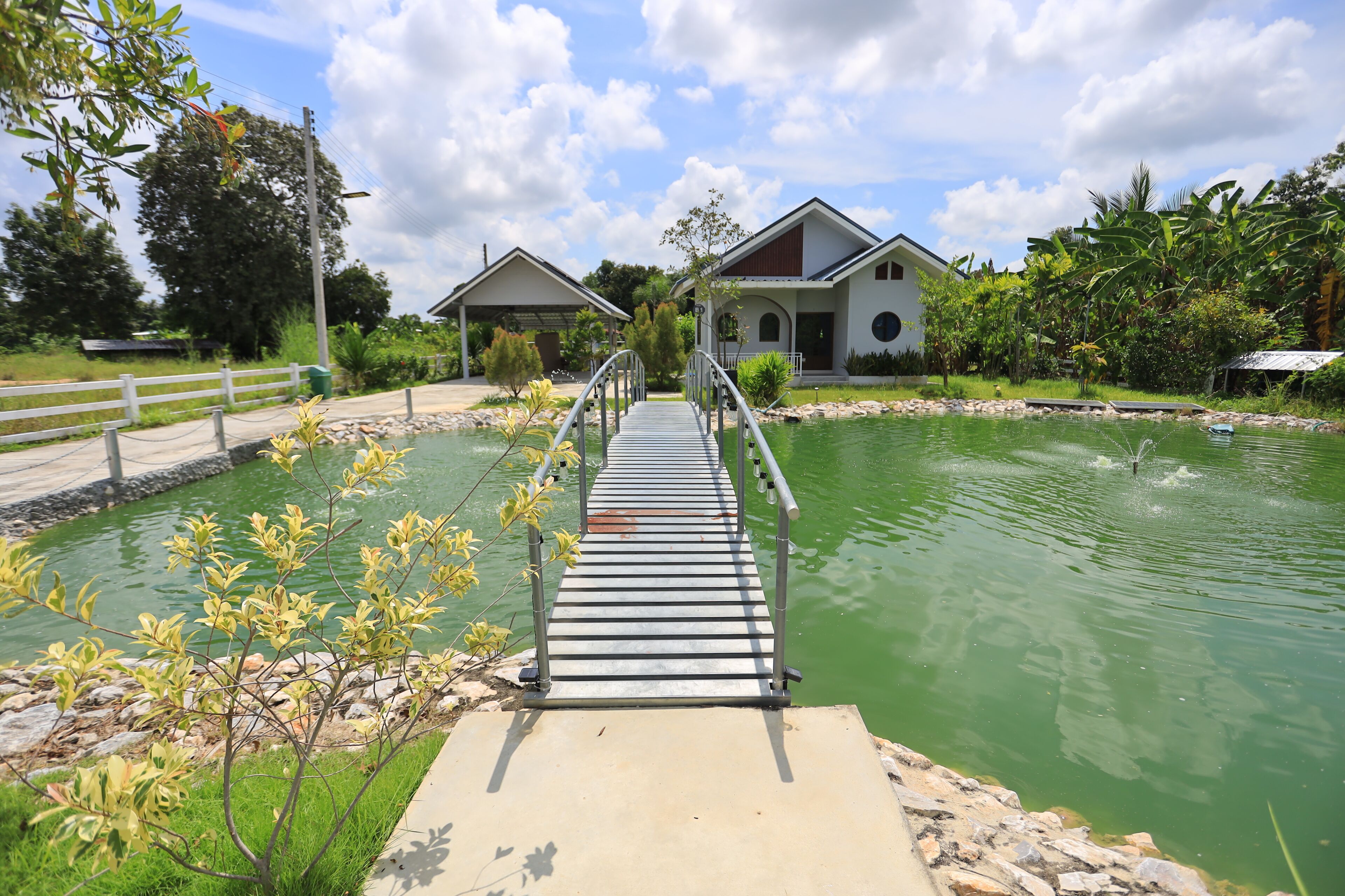 A wooden bridge leading to a building with a pool.