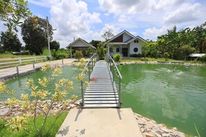 A wooden bridge leading to a building with a pool. - Numhom Resort (Thap Than)