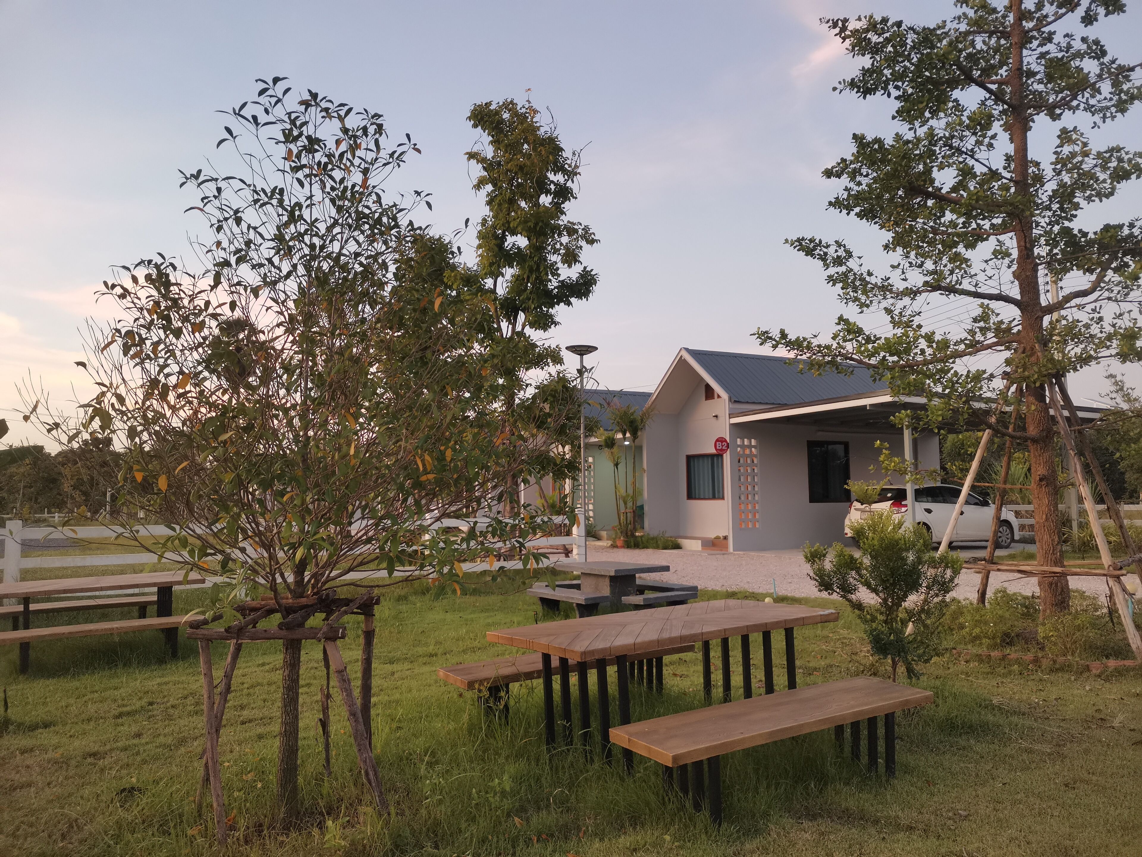 A small, modern building with a flat roof, surrounded by a grassy area with picnic tables and benches.