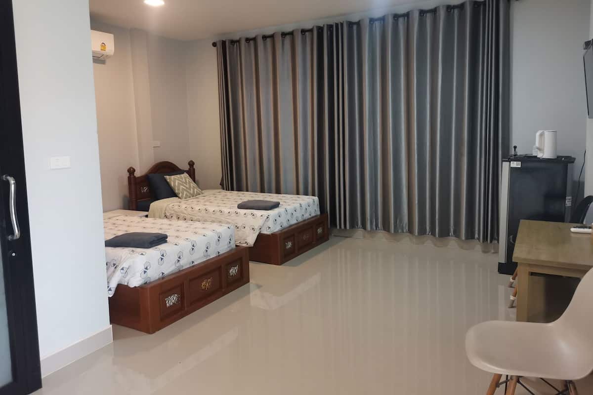 A hotel room with two beds, a desk, a chair, a coffee machine, and a TV.
