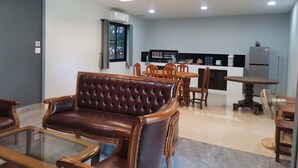 Un salon moderne avec un canapé en cuir, une table basse en verre et un coin repas comprenant des chaises et une table en bois.