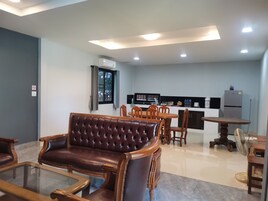 Una sala de estar moderna con un sofá de cuero, una mesa de centro de vidrio y un comedor con sillas y una mesa de madera.