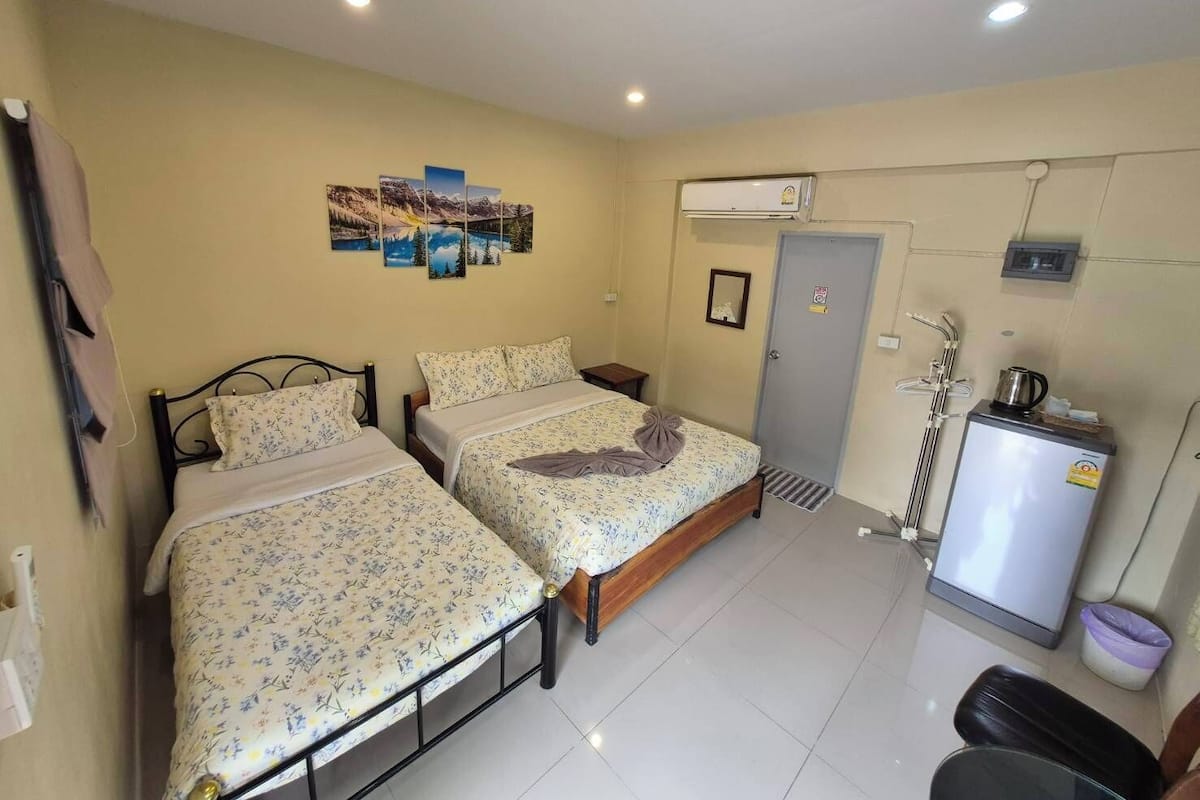 A room with two beds, a small refrigerator, a heater, and a door with a mirror.