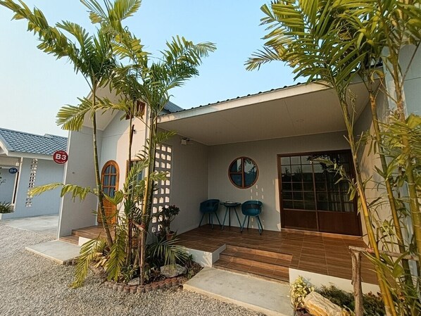 A modern house with a covered porch, two blue chairs, and a large window. - Numhom Resort (Thap Than)