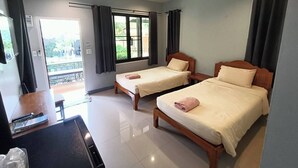 Une chambre d’hôtel avec deux lits, un bureau et une vue sur l’extérieur.