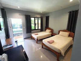 Habitación de hotel con dos camas, un escritorio y vistas al exterior.