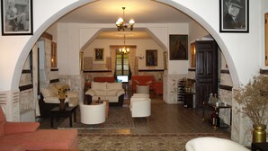A spacious living room with a high arched ceiling, a fireplace, and a view of the dining area. - Gran Posada La Mesnada (Olmedo)
