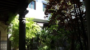 A courtyard with potted plants, a pool, and a building in the background. - Gran Posada La Mesnada (Olmedo)