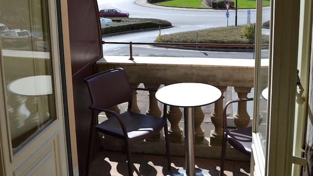 Un balcón con vistas a una carretera y edificios, una mesa y dos sillas.