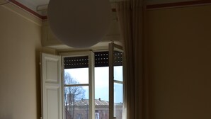 Habitación de hotel con cama, escritorio, televisor y vista a la calle a través de una puerta.