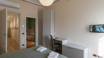 Une chambre d’hôtel équipée d’un lit, d’un bureau, d’une chaise, d’une télévision et d’une armoire.