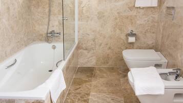 Un baño moderno con bañera, inodoro y lavamanos, todo en color blanco.