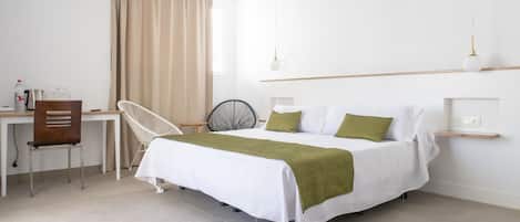 A modern hotel room with a bed, a desk, a chair, and a small shelf.