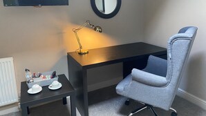 A small, modern room with a desk, chair, and a TV mounted on the wall. - The White Swan (Leeds)