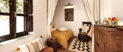 Una camera da letto con un letto, un armadietto in legno, una finestra con tende, un tappeto e un quadro appeso al muro.