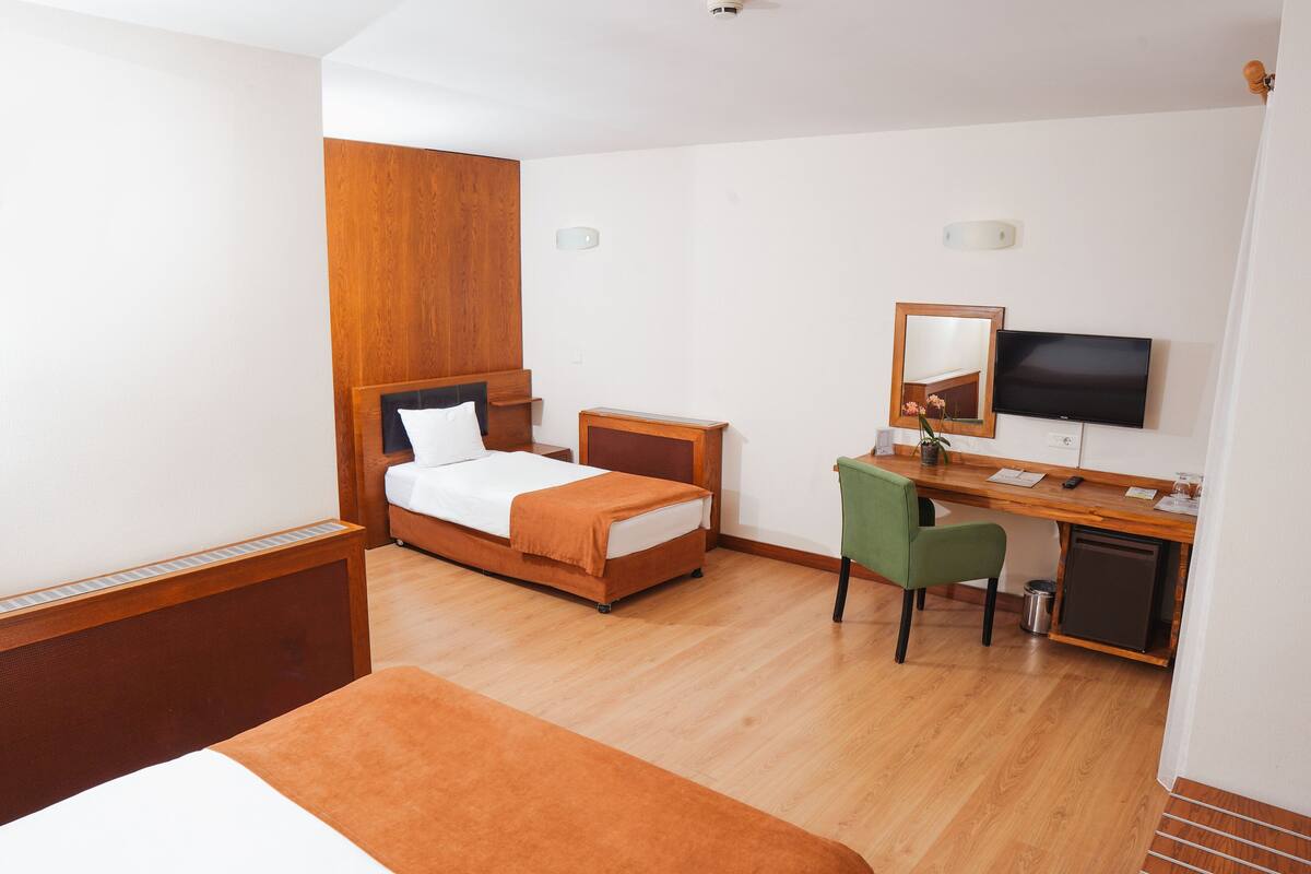 A hotel room with a bed, a desk with a chair, a television, and a small refrigerator.