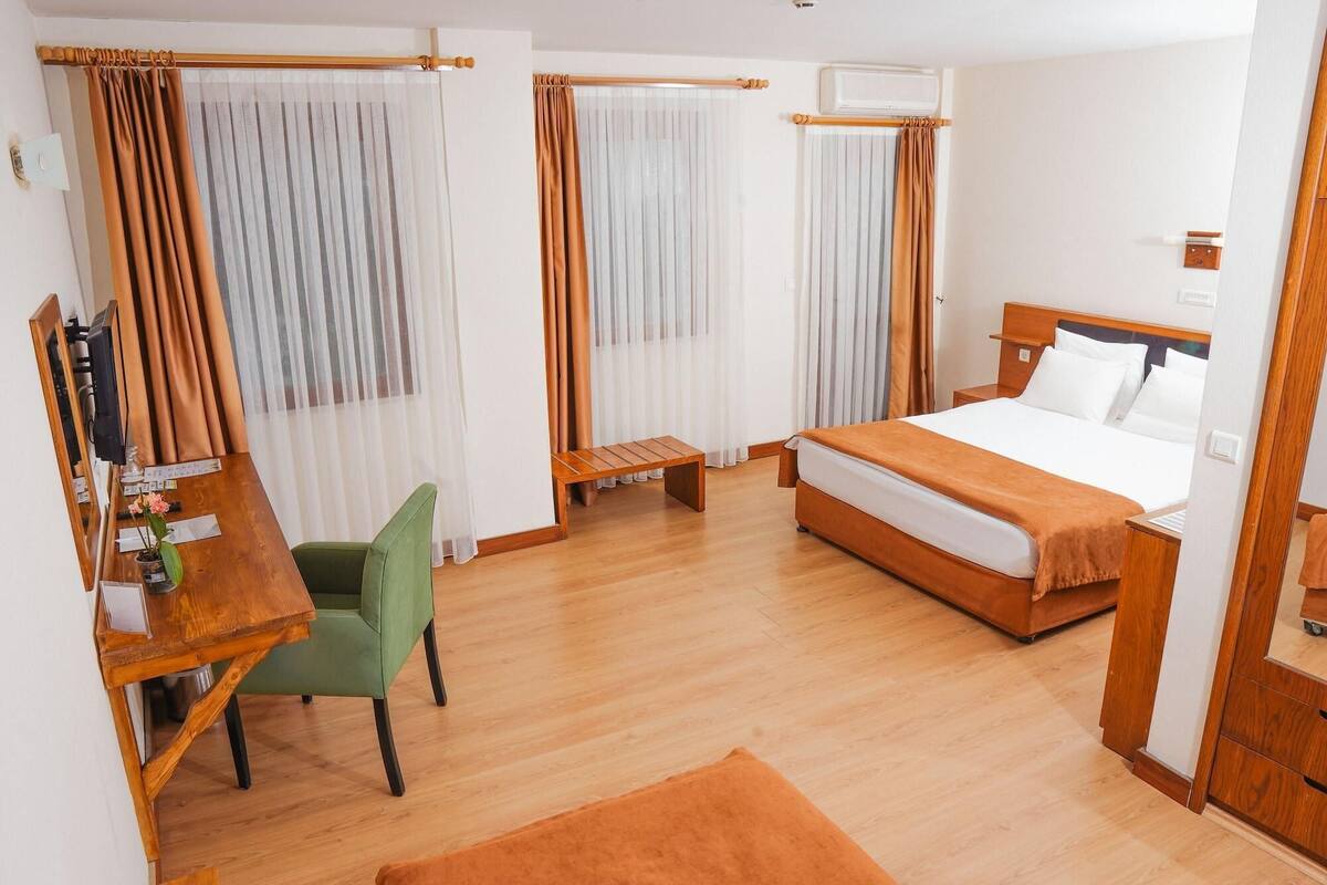A hotel room with a bed, desk, chair, and a small table.