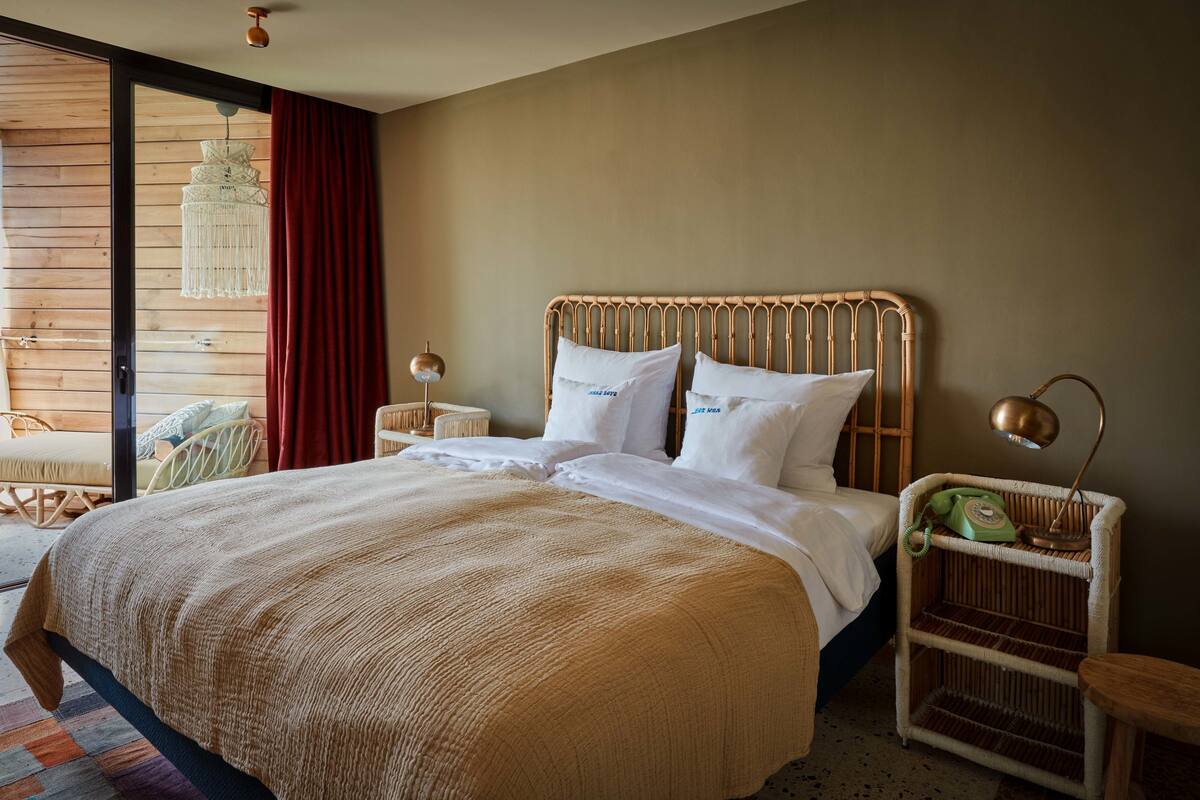 A bedroom with a large bed, a wicker nightstand, and a chair.