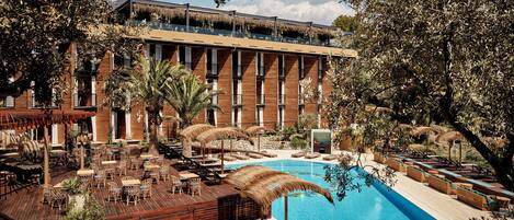 A resort with a swimming pool, outdoor seating, and a building with multiple windows.