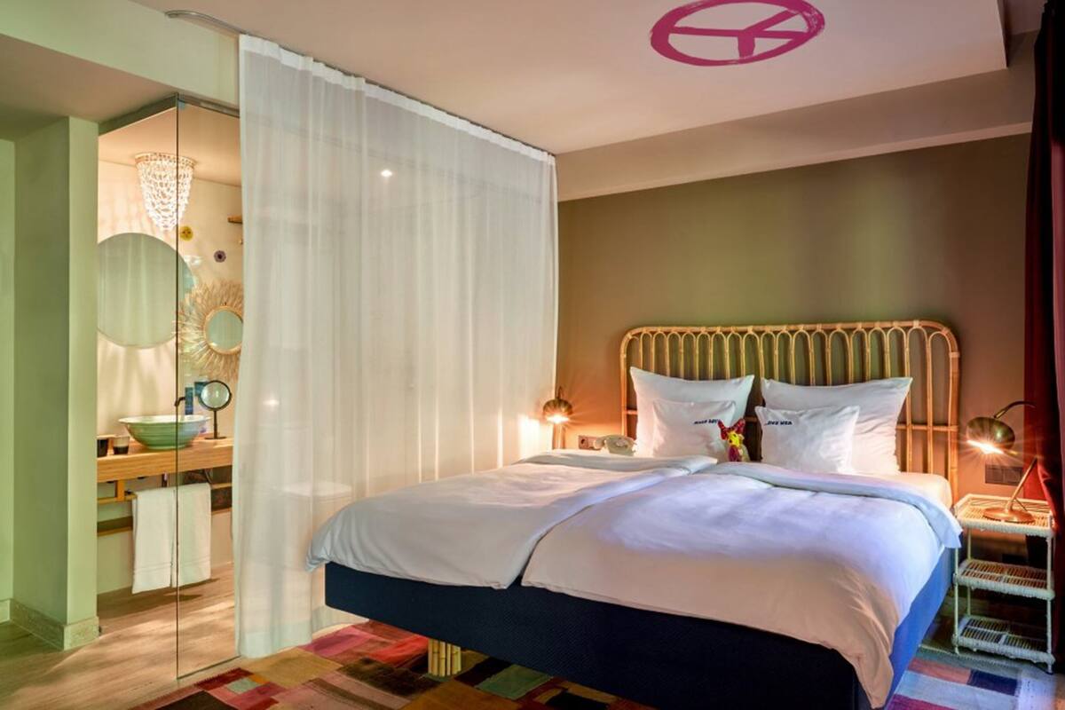 A modern bedroom with a large bed, a glass shower enclosure, and a bedside table with a lamp.