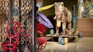 A room with a decorative elephant sculpture, wicker furniture, and various patterned vases.