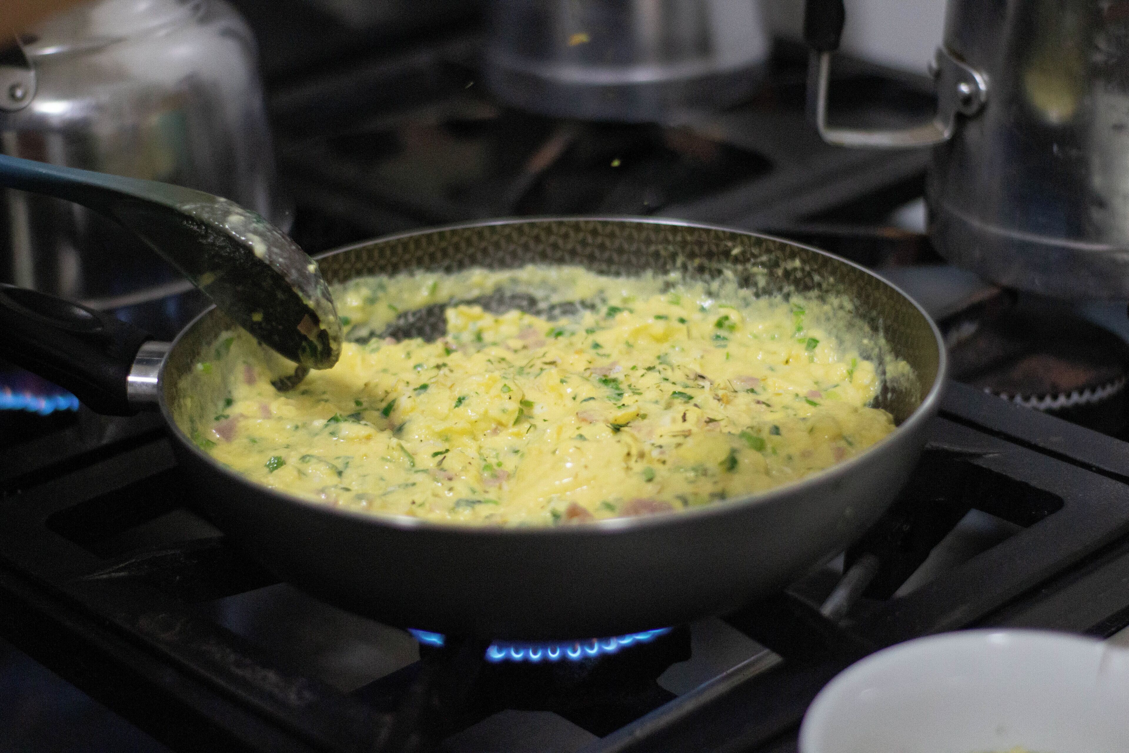 Une poêle sur une cuisinière, dans laquelle un mélange est en train d’être remué.