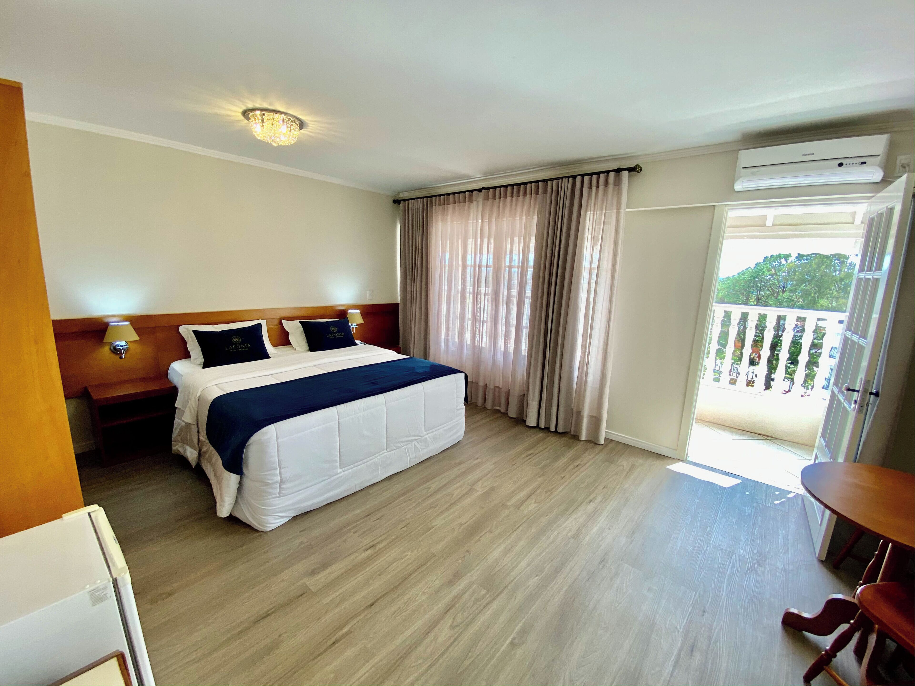 Ein Hotelzimmer mit Bett, Nachttischen, einer Lampe, einer Klimaanlage und einem Balkon mit Blick.