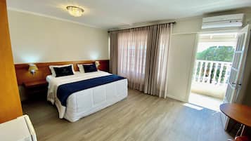 Ein Hotelzimmer mit Bett, Nachttischen, einer Lampe, einer Klimaanlage und einem Balkon mit Blick.