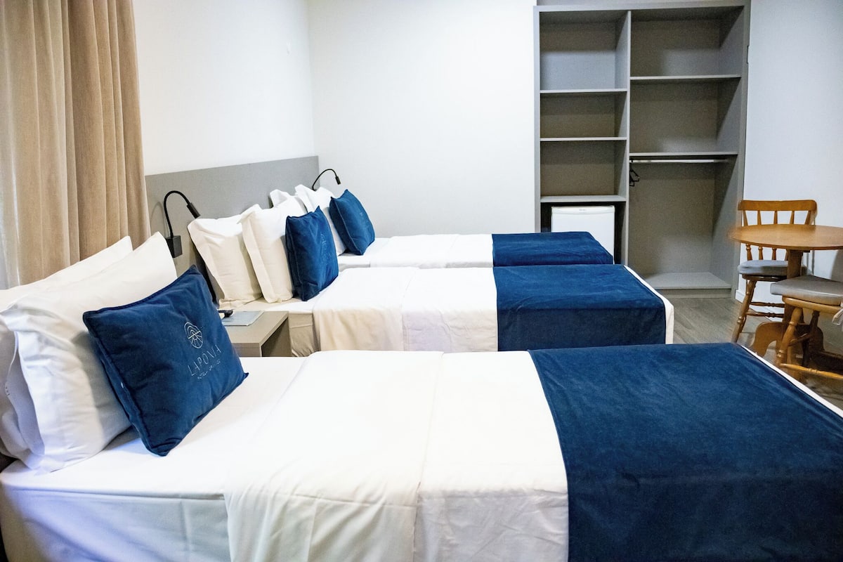 A hotel room with two beds, a chair, and a wardrobe.
