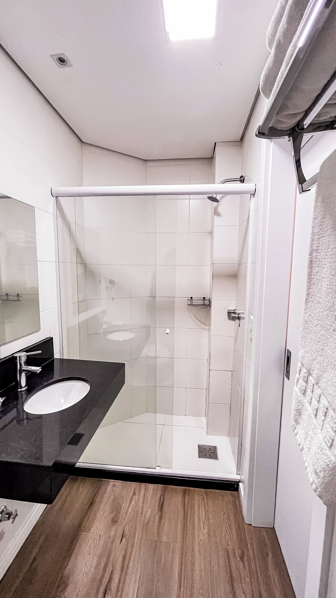 A modern bathroom with a glass shower enclosure, a black countertop sink, and a large mirror.