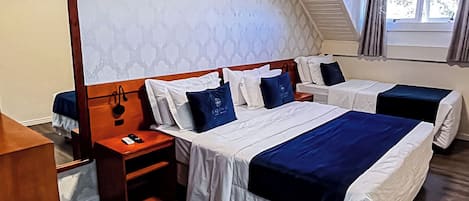 A hotel room with two beds, a wooden desk, a mirror, and an air conditioning unit.
