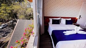 A hotel room with a bed, a nightstand, and a view of the street and trees. - Laponia Hotel Gramado (Gramado)