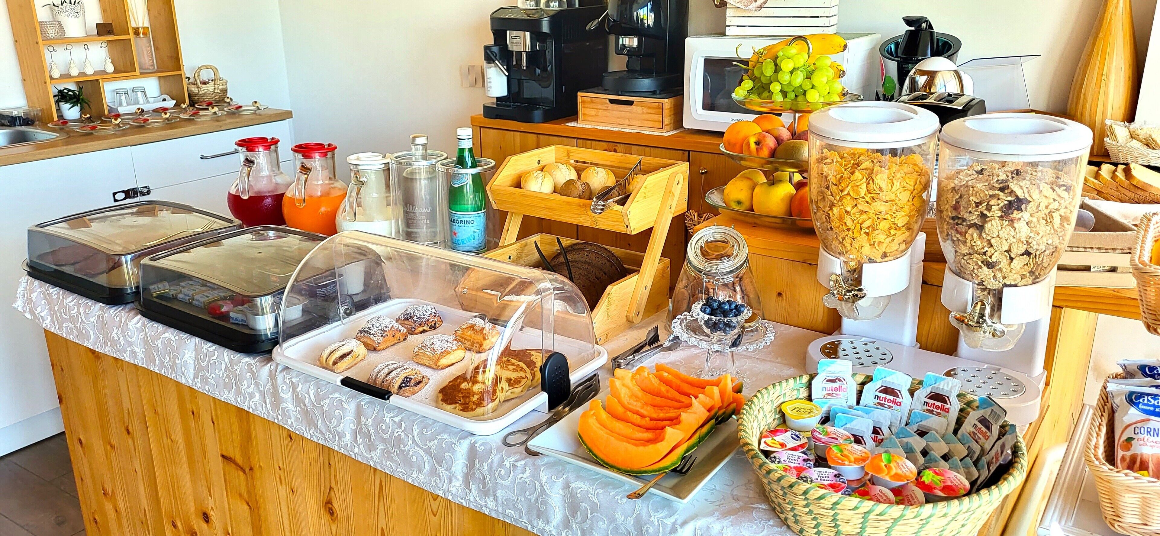 A buffet with various food items, including pastries, fruits, and cereals.