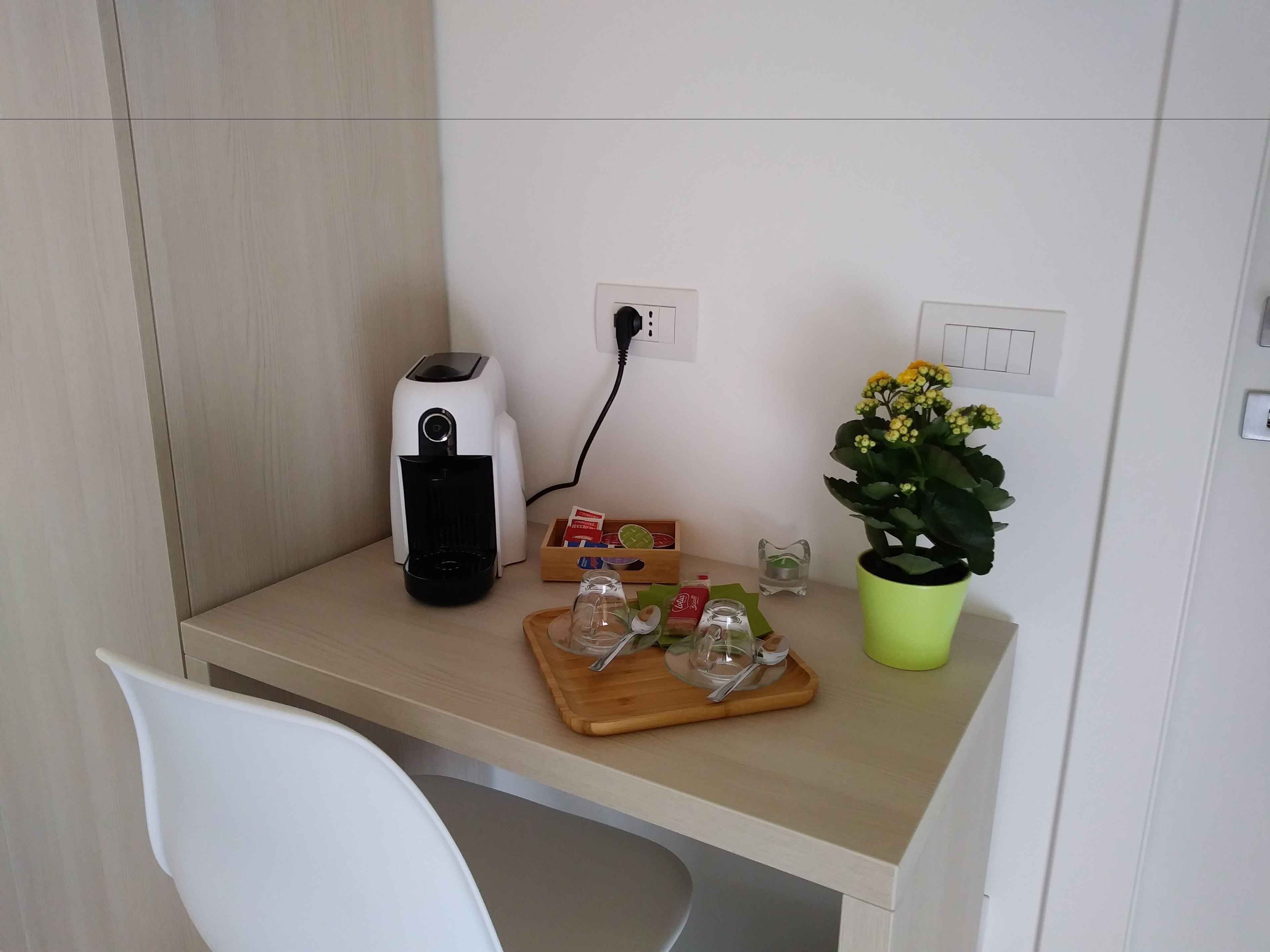 Una kitchenette pequeña con cafetera, una planta en maceta y una bandeja con salsas.